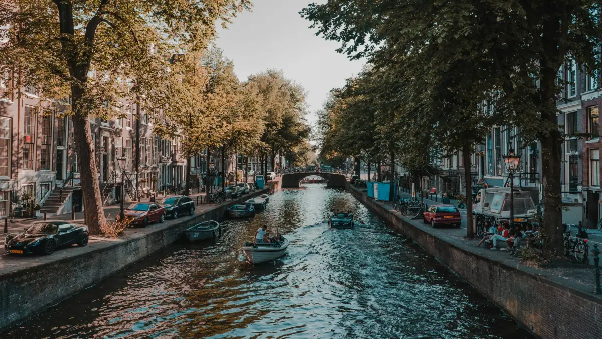 Tree-lined Amsterdam canal with boats and historic canal houses