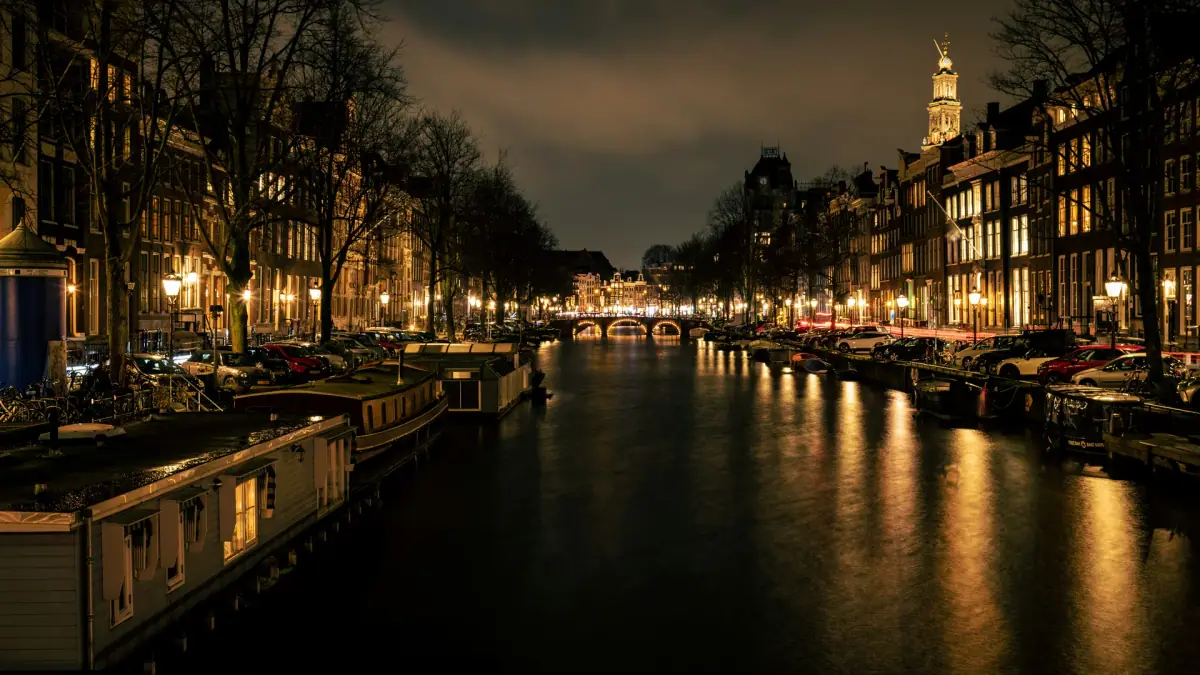 Lights reflected in the Prinsengracht at night, with the Westerkerk tower above Amsterdam's canal houses
