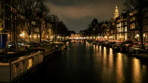 Licht weerspiegeld in de Prinsengracht bij nacht, met de Westertoren boven de Amsterdamse grachtenpanden