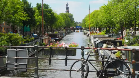 Houseboats on the Prinsengracht with the Westerkerk tower and a bicycle on a bridge