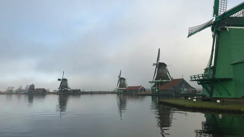 Moulins à vent se reflétant dans l'eau à Zaanse Schans sous un ciel gris et brumeux