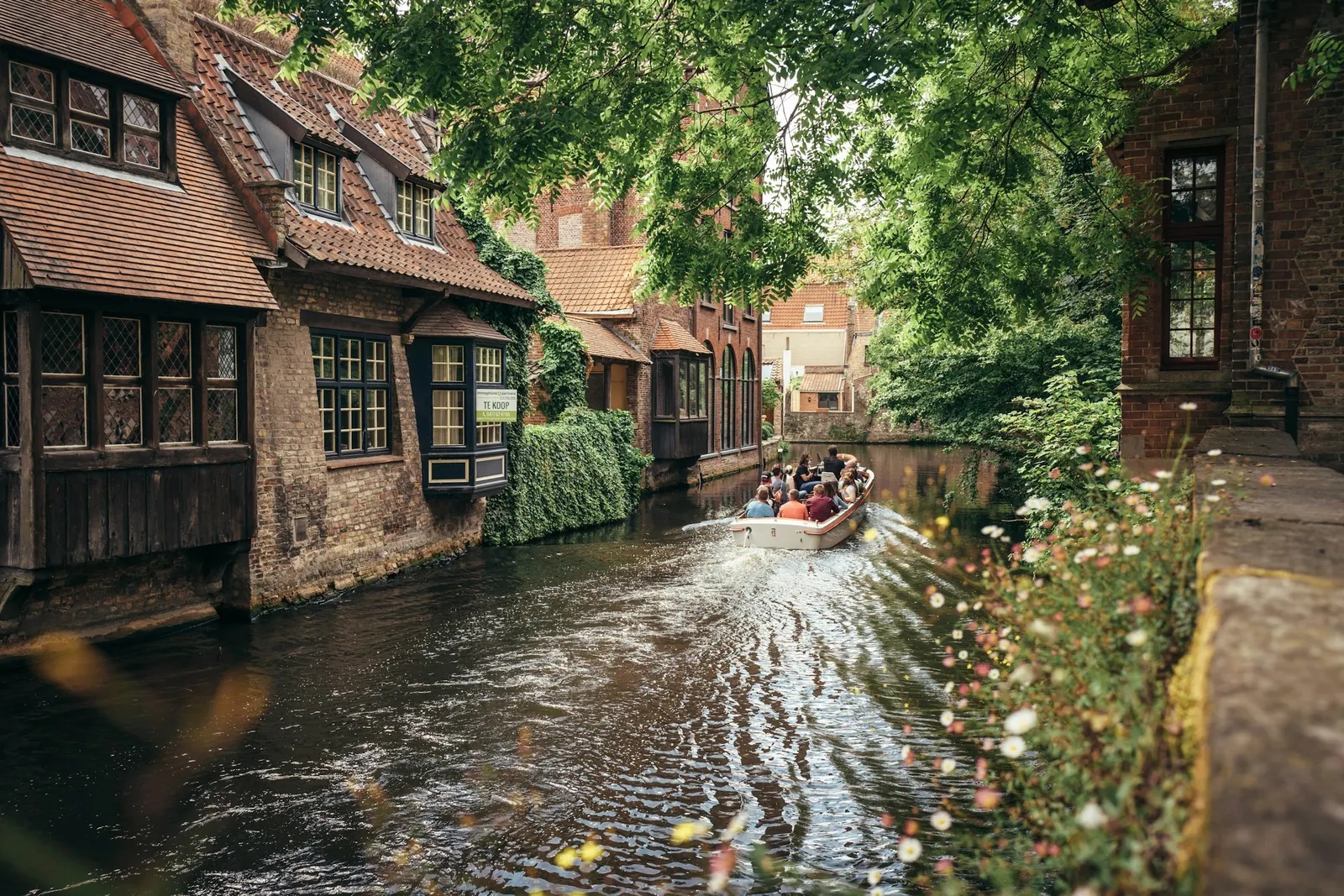 Een rondvaartboot tussen oude bakstenen huizen in Brugge