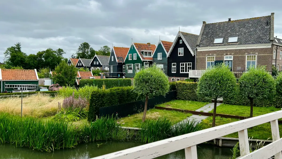 Wooden houses and a white footbridge beside a canal in Marken