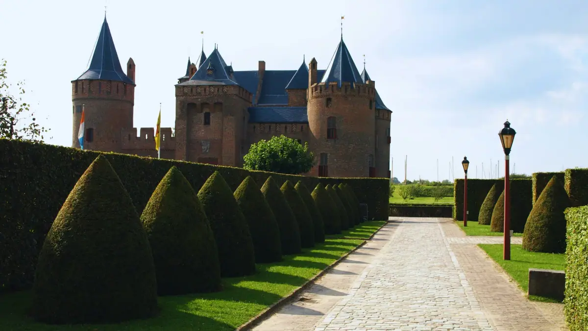 Het Muiderslot gezien vanaf een pad tussen gesnoeide tuinhagen
