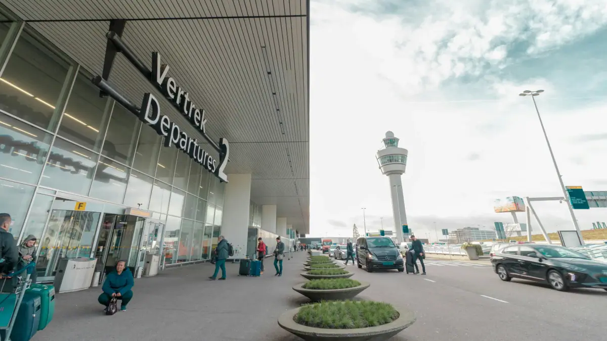 Vertrekhal 2 van Schiphol met reizigers en de verkeerstoren