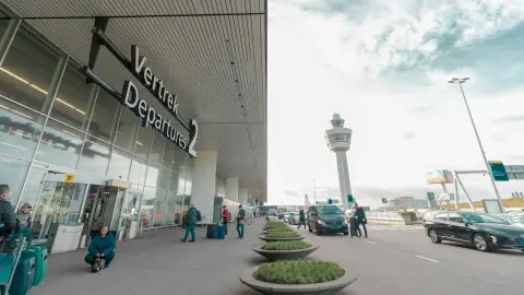 Vertrekhal 2 van Schiphol met reizigers en de verkeerstoren